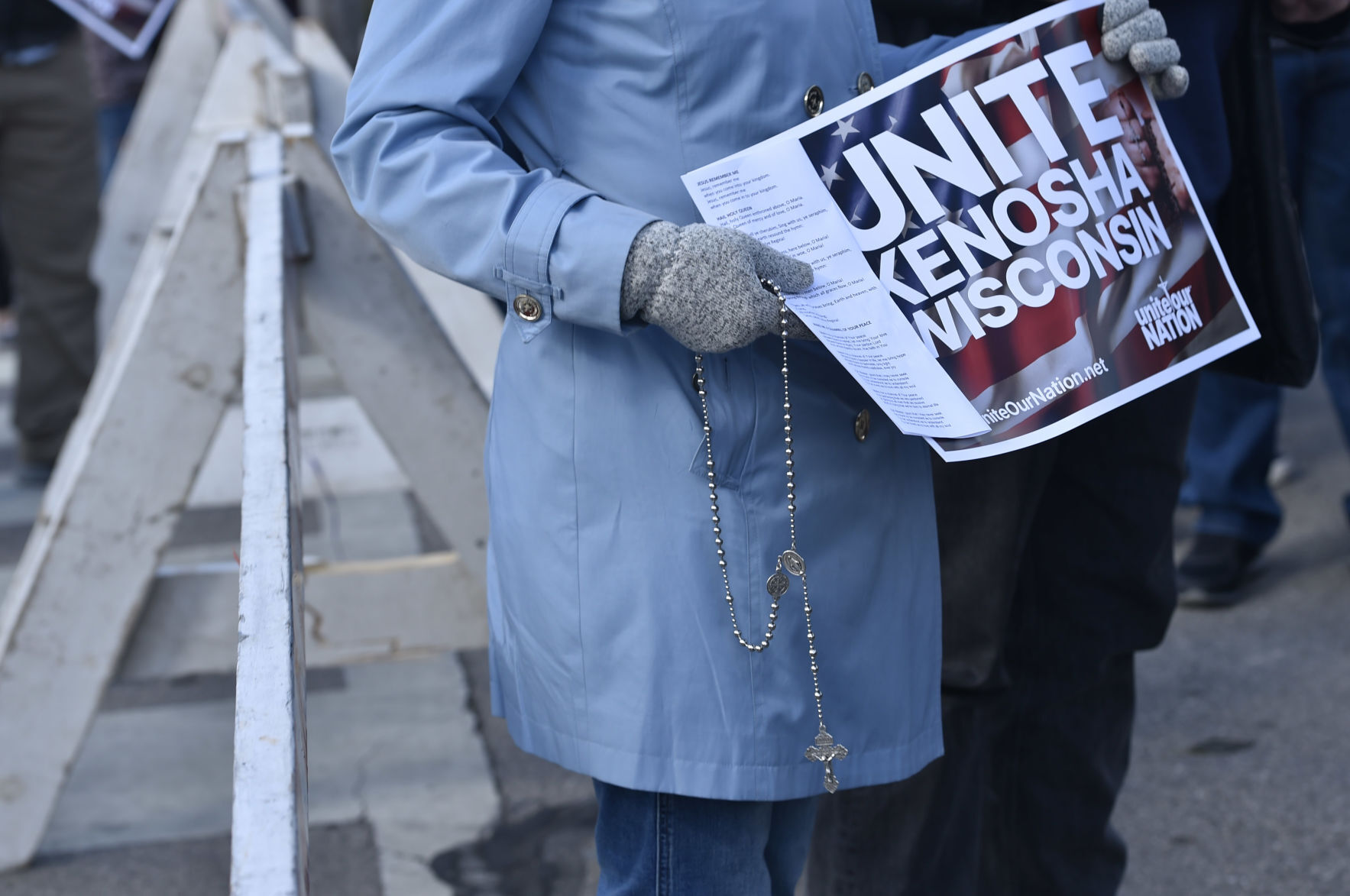 Holding a rosary and a sign